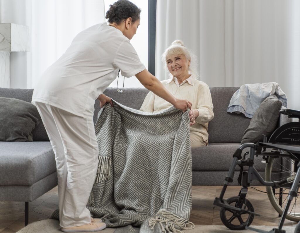 Caregiver assisting elderly woman with blanket